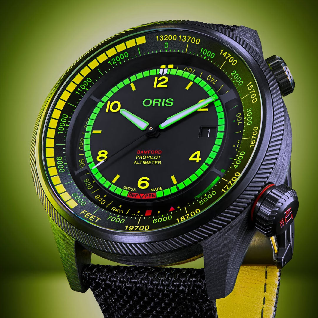 A close-up of the ORIS Propilot X BWD Limited Edition Automatic Winding 47mm Watch, featuring a black case, yellow and green detailing, and a yellow-accented strap, set against a green gradient background. The dial displays both feet and meter altitudes.