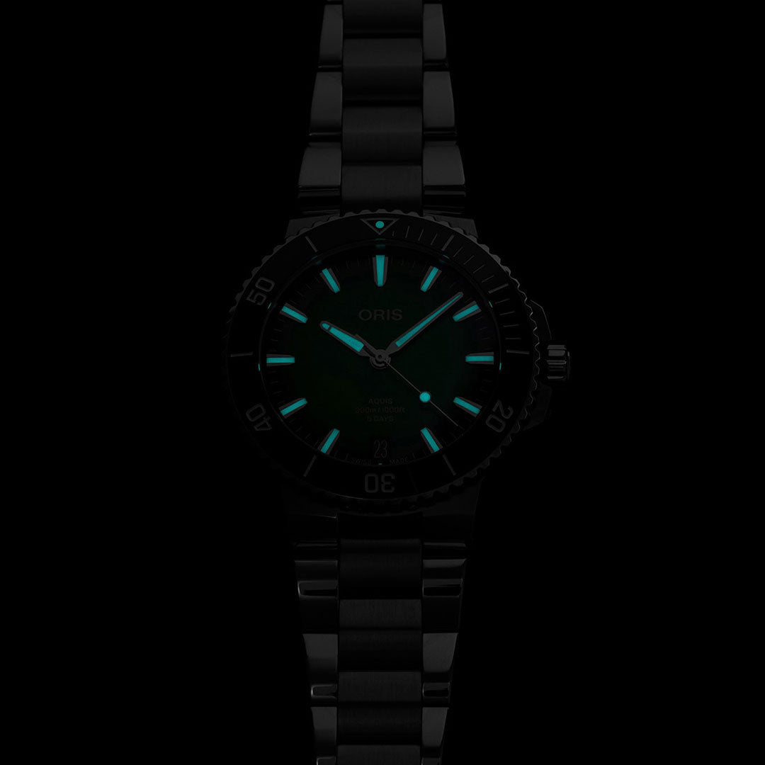 The Oris Aquis Date Calibre 400 Automatic Winding 43.5mm Watch by ORIS features a black automatic design with luminous markers and hands that glow green in the dark. Its metal band beautifully complements the round face and marked bezel, offering an impressive five-day power reserve that seamlessly blends elegance with functionality.