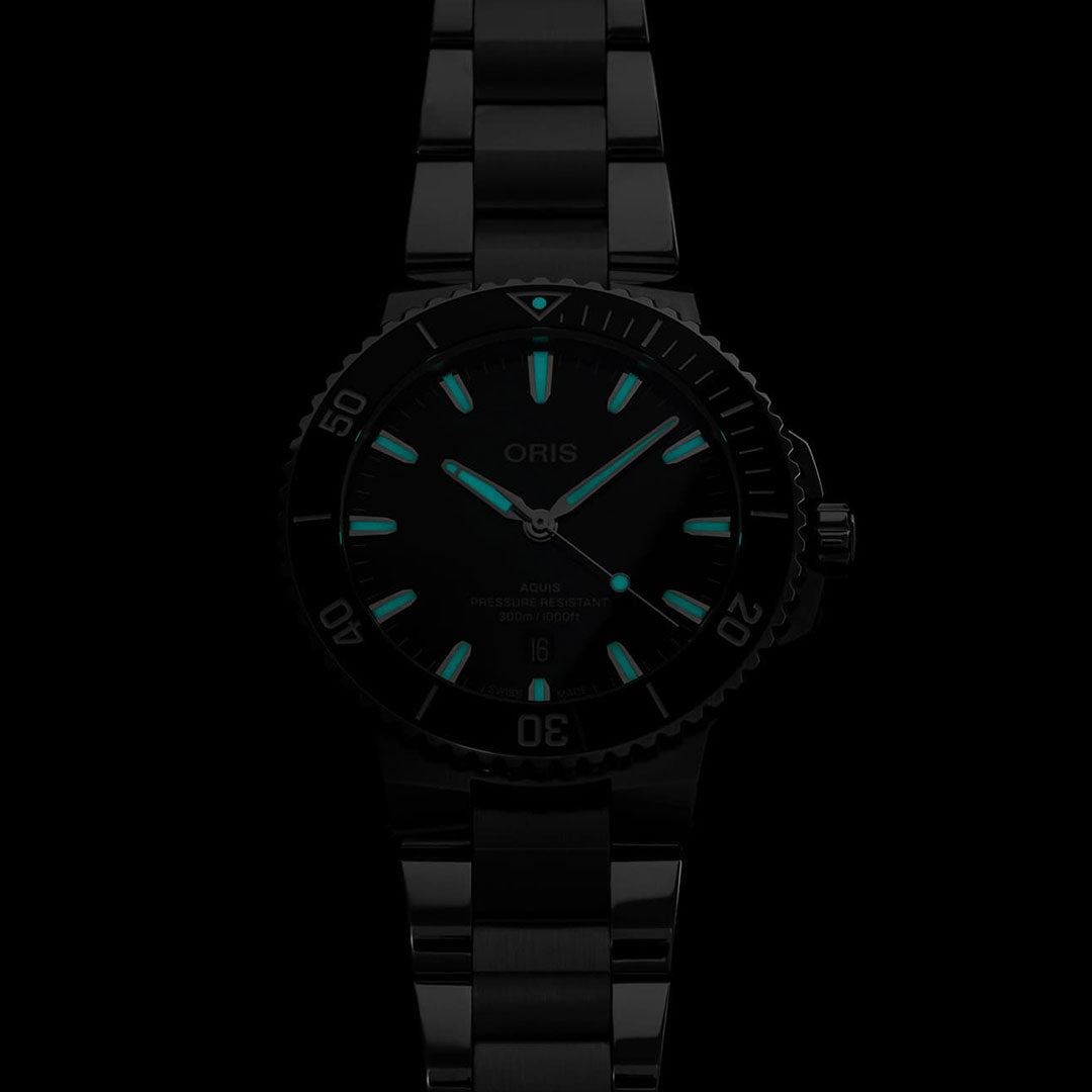The Oris Aquis Date Automatic Winding 43.5mm Watch features a sleek, modern design with a black metal bracelet and water-resistant capabilities. It showcases glowing green hour markers and hands against a dark face, with the brand name "ORIS" prominently displayed.