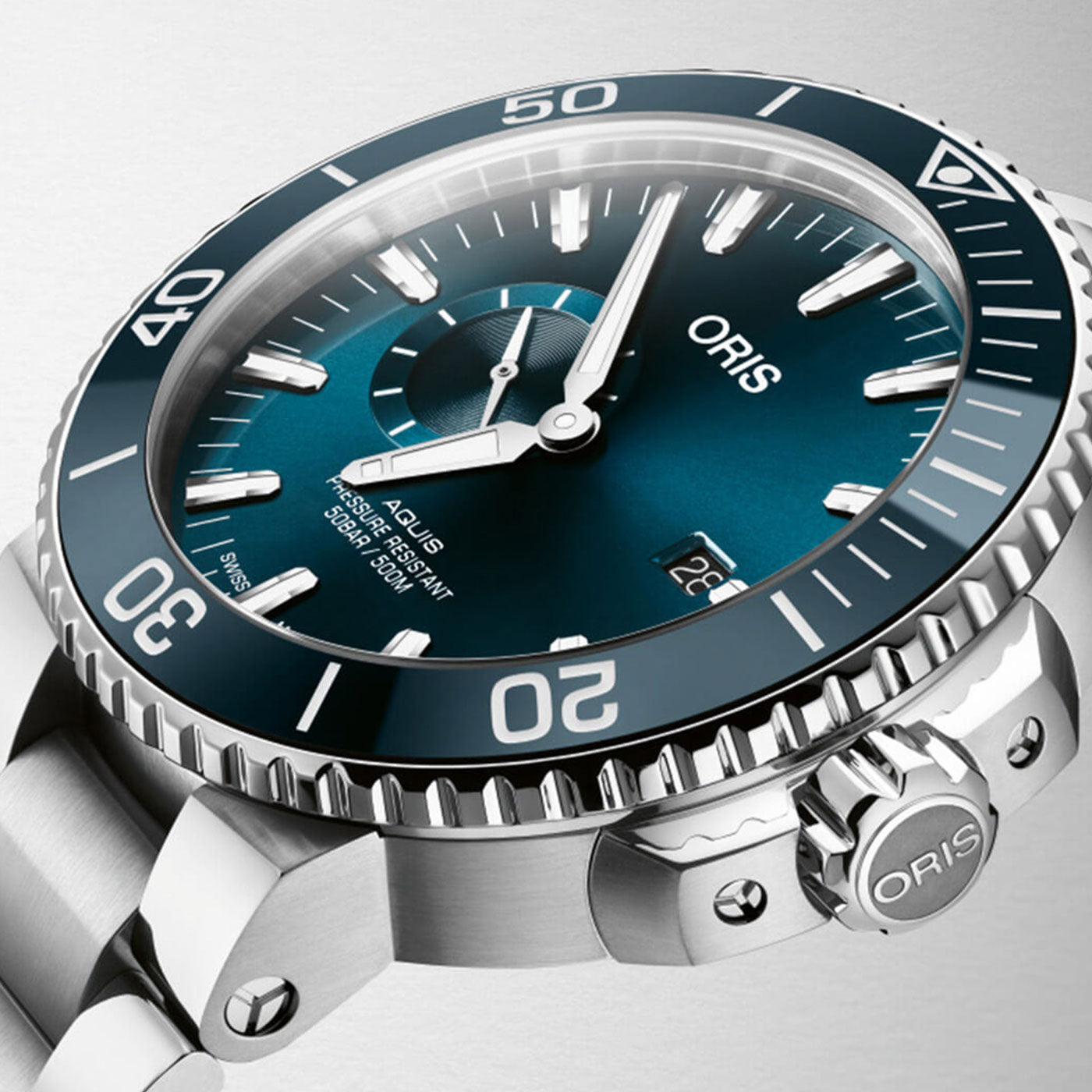 Close-up of the Oris Aquis Small Second Date Automatic 45.5mm watch by ORIS, showcasing a silver divers timepiece with a blue dial, luminescent hour markers, a date window at 6 o'clock, and a rotating bezel. The watch is equipped with a stainless steel bracelet and has a prominent side crown.