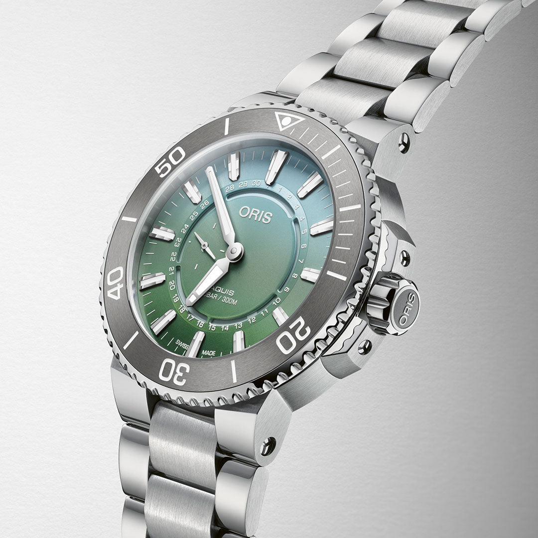 A close-up of the Oris Aquis Dat Watt Limited Edition II Automatic Winding 43.5mm Watch reveals a stunning silver and green gradient dial. With numeral markers, a date window, and a stainless steel bracelet, this elegant timepiece proudly displays the brand name "ORIS" on its face—a true nod to precision and conservation.
