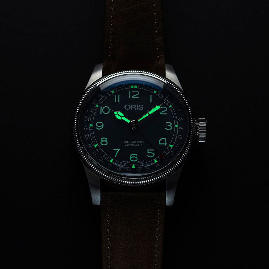 The Oris Big Crown Pointer Date Automatic Winding 44mm Watch by ORIS boasts a dark face with a luminous dial, making it ideal for low light conditions. Its glowing green hands and numerals are highlighted by an oversized crown, along with a black leather strap and polished metal bezel.