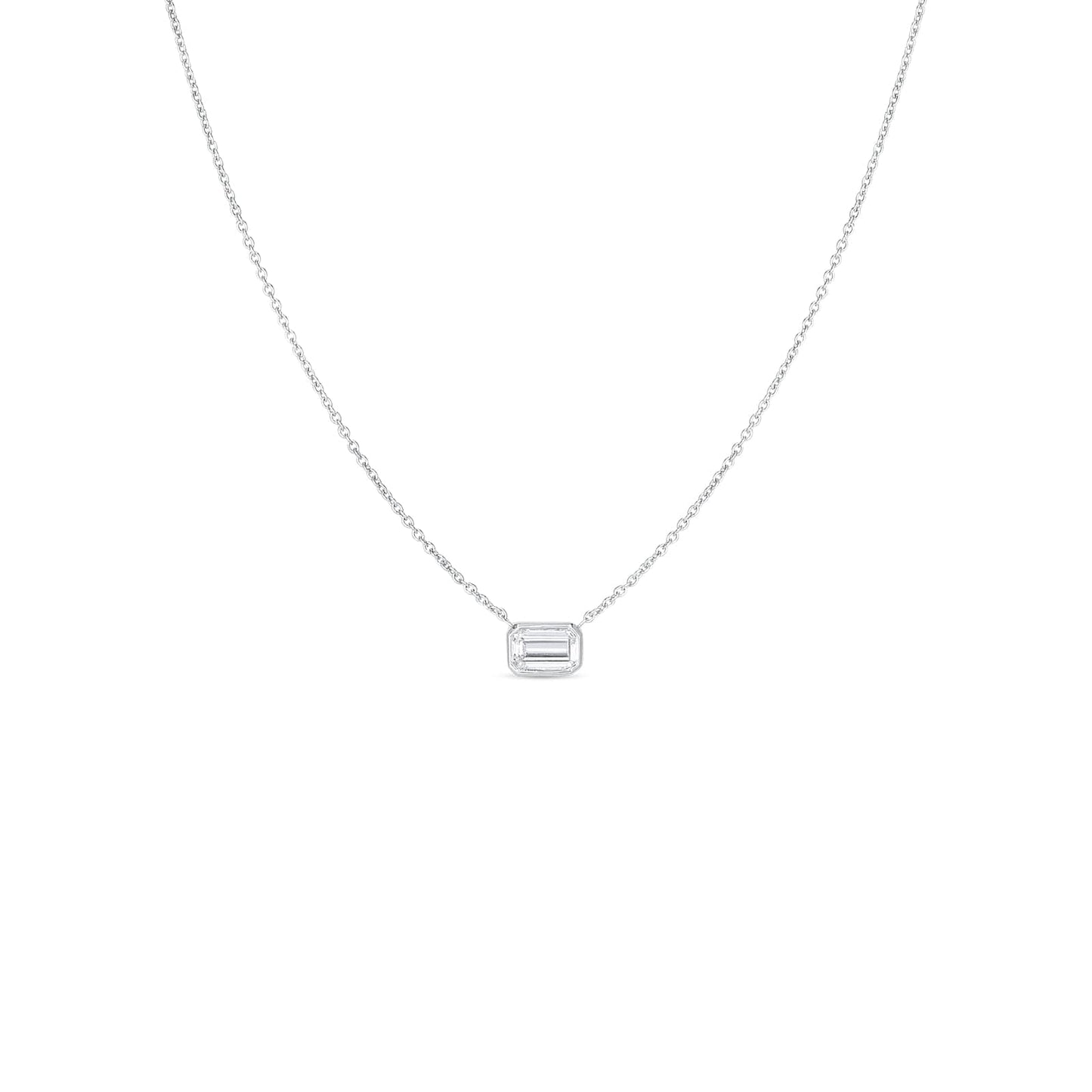 The Roberto Coin Diamonds By The Inch 18K White Gold Large Emerald Cut Diamond Necklace Pendant is a sophisticated piece from the renowned brand Roberto Coin. This delicate silver necklace showcases a prominent rectangular pendant adorned with an emerald-cut diamond, crafted in elegant 18k white gold. Placed against a simple white background, the design exudes minimalist elegance and charm.
