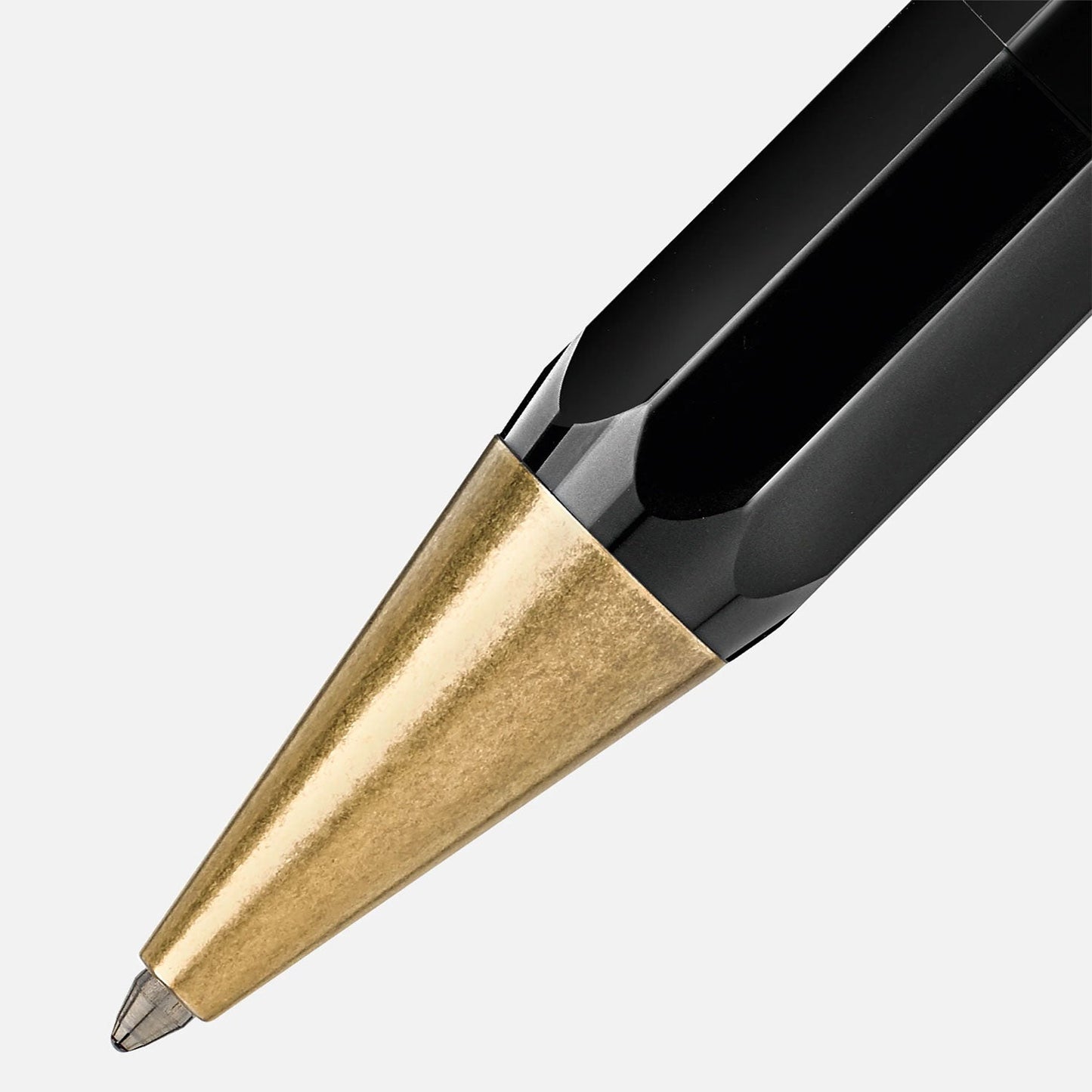 Close-up of the Montblanc Heritage Egyptomanian Special Edition Black Ballpoint Pen, showcasing its octagonal-shaped pen tip with a gold-colored metal point and a glossy black body, set against a plain white background.