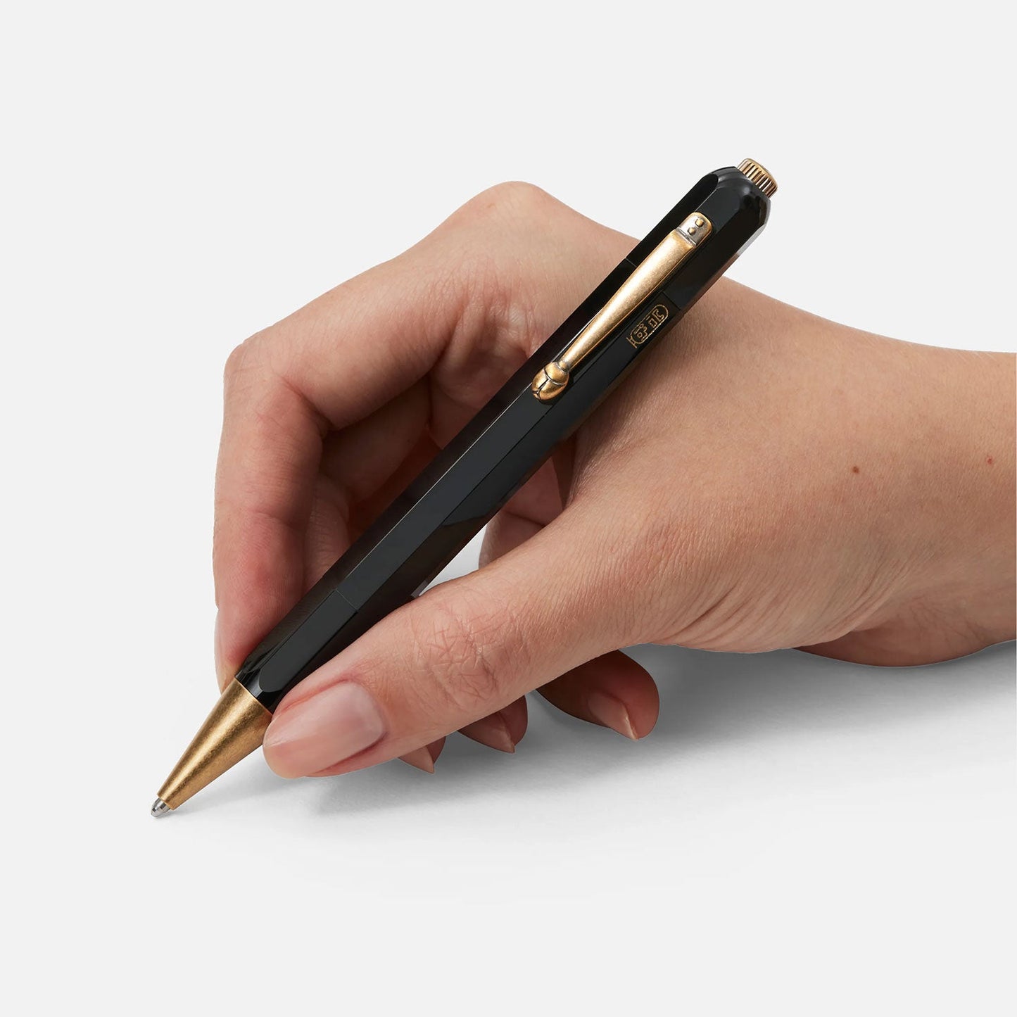 A hand holds a Montblanc Heritage Egyptomanian Special Edition Black Ballpoint Pen, poised above a blank white surface.
