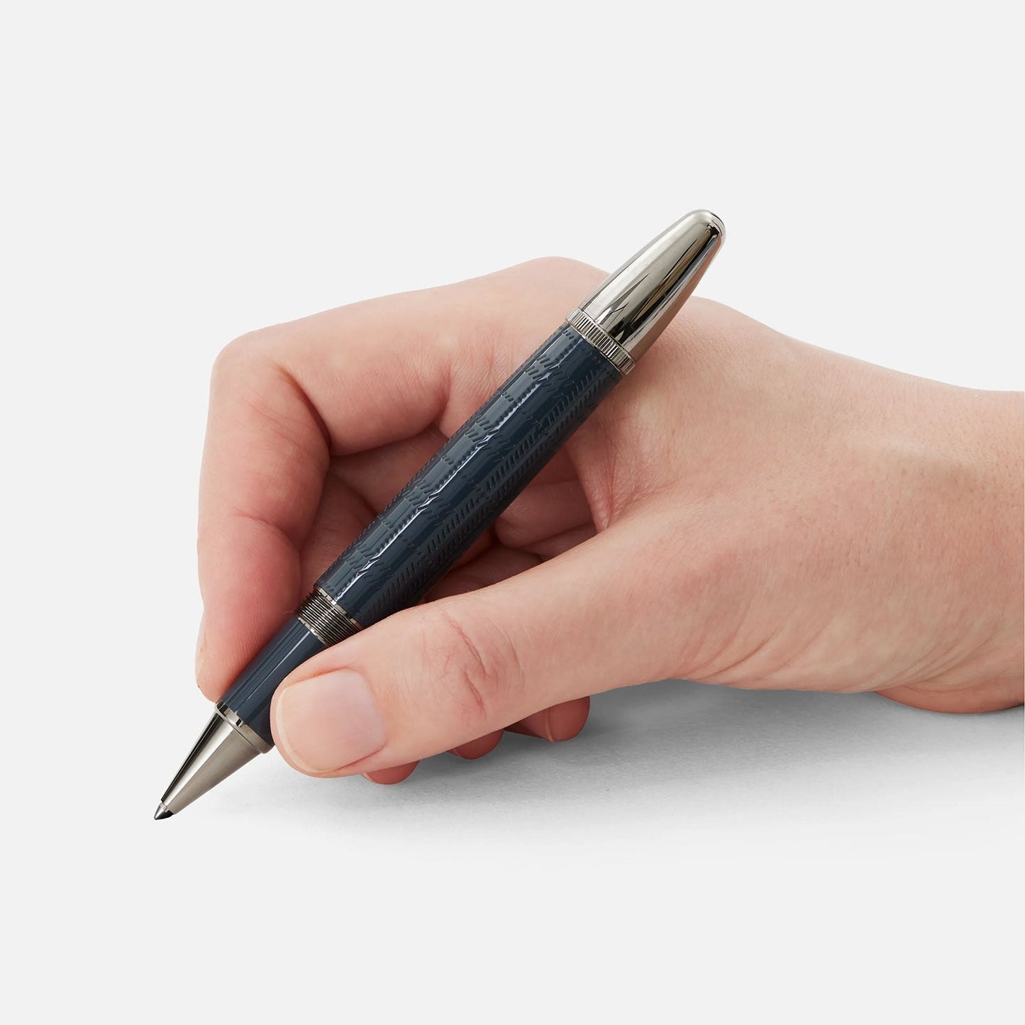 A hand holding a sleek, dark-colored Montblanc Writers Edition Sir Arthur Conan Doyle Limited Edition Rollerball Pen with silver accents against a white background celebrates the legacy of Sir Arthur Conan Doyle.