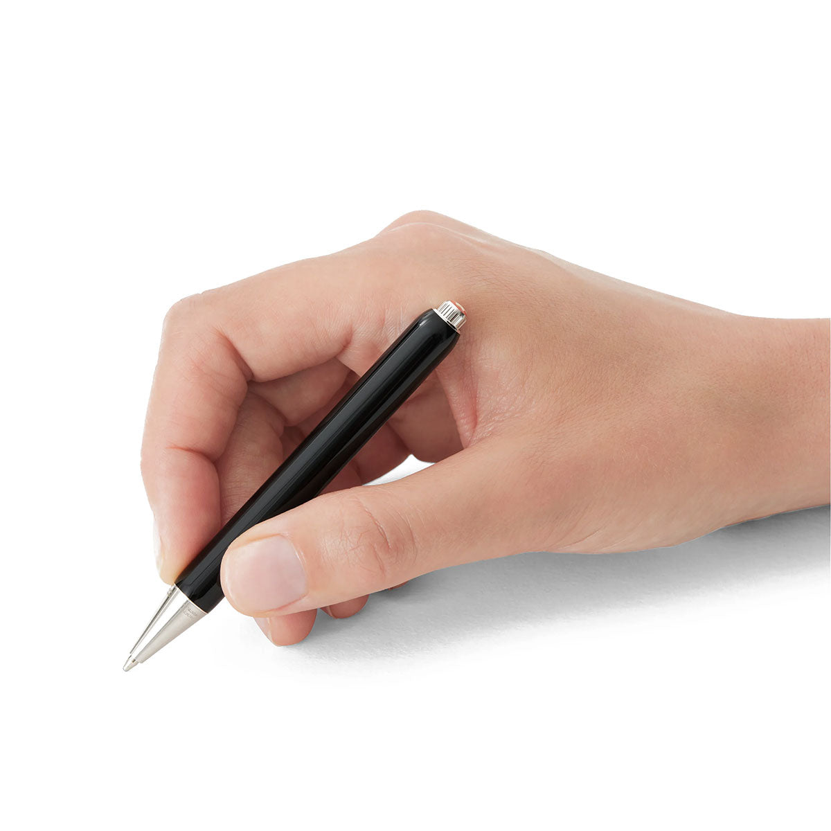 A hand holding a Montblanc Heritage Rouge et Noir Baby Special Edition Black Ballpoint Pen is poised to write on a blank white surface.