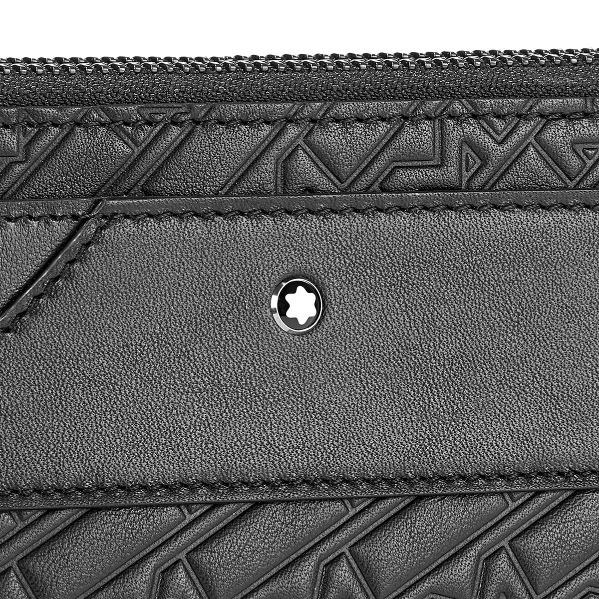 Close-up of a Montblanc M-Gram Leather Clutch Bag in black, showcasing embossed geometric patterns. This elegant clutch features a zipper and is adorned with a small, circular metal emblem inspired by the M-Gram 4810 star-like design at the center.