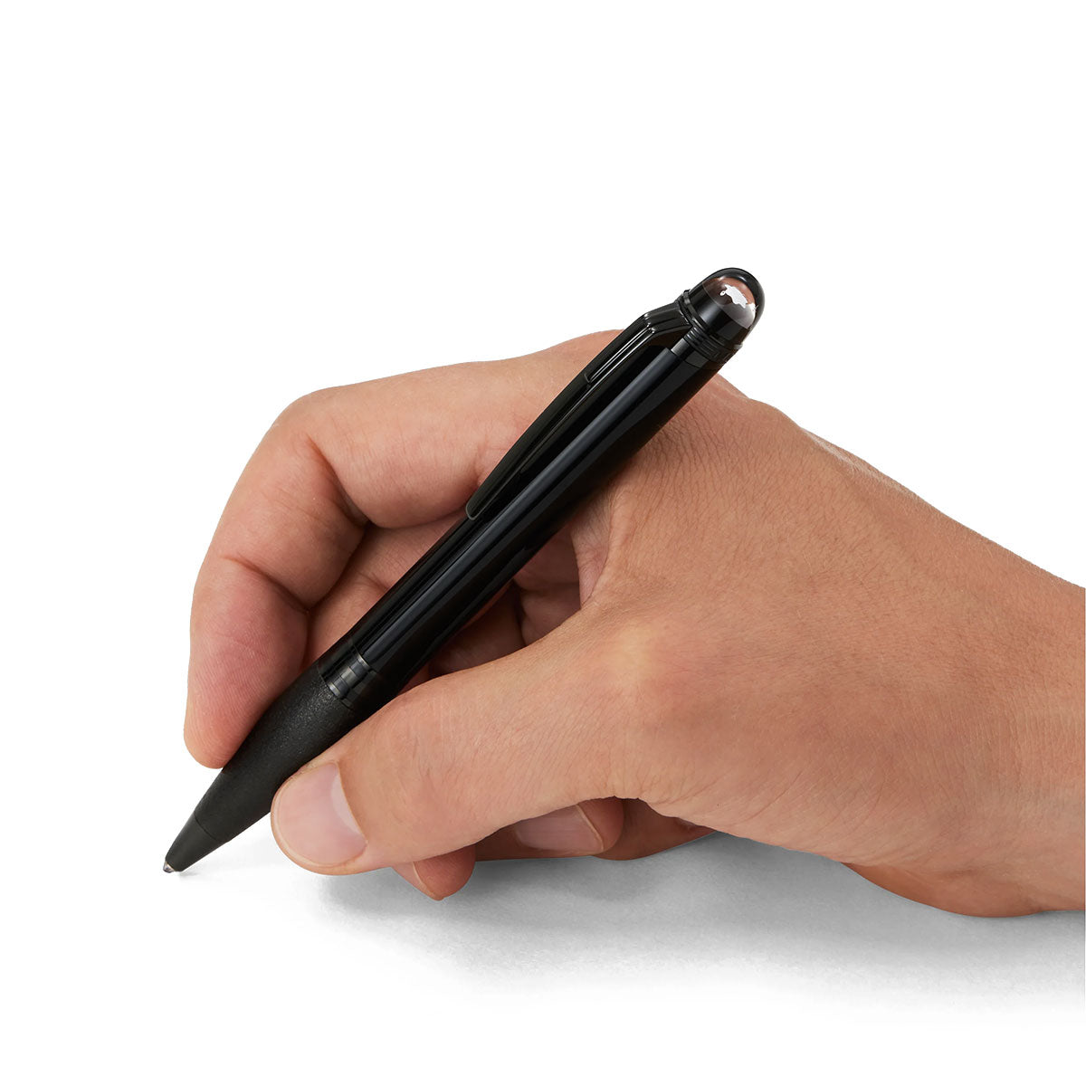 A hand holding a sleek Montblanc StarWalker Black Cosmos Doue Ballpoint Pen poised above a blank white surface, ready to write.