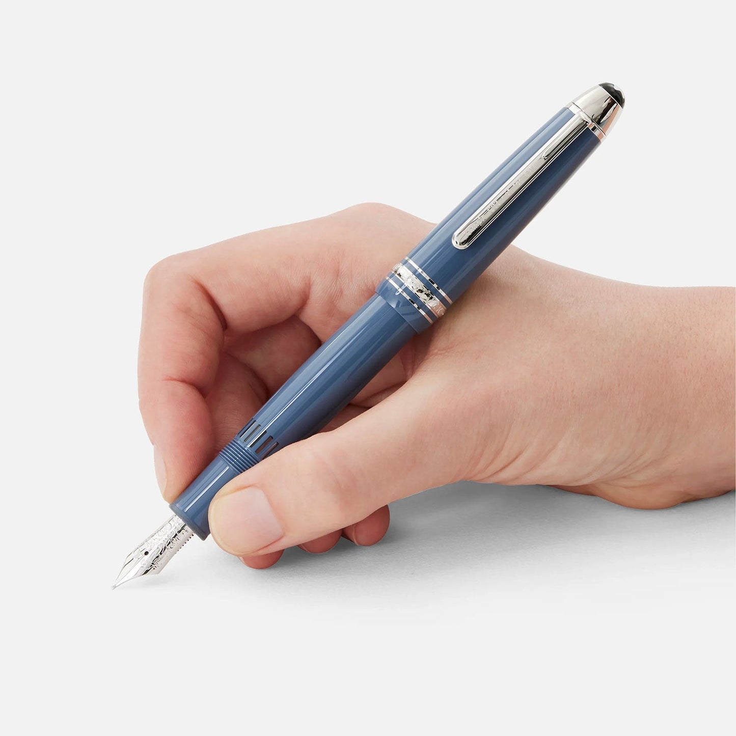 A hand holds a Montblanc Meisterstuck Glacier LeGrand Blue Fountain Pen against a plain white background, with its silver accents and visible nib elegantly pointing towards the bottom left corner of the image.