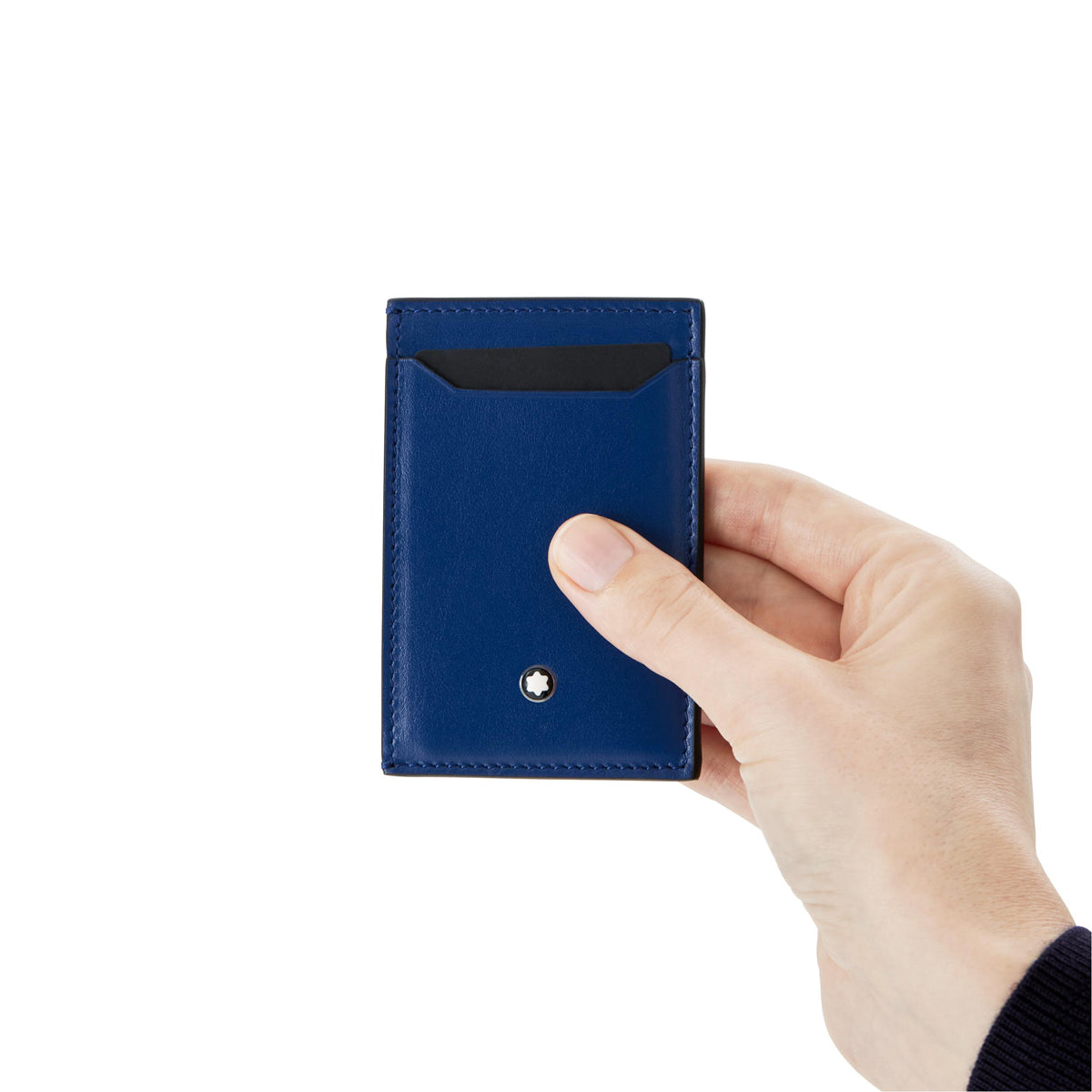 A hand holds the Montblanc Meisterstück Blue Leather Pocket 3CC Card Holder, which is slim and adorned with Montblanc's small metal emblem near the bottom. The card holder features a blue pocket design and showcases a visible card slot at the top against a white background.