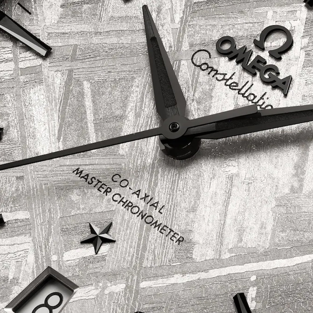 Close-up of the OMEGA Constellation Co-Axial Master Chronometer 41mm Watch, featuring black hands, a star emblem, and a silver meteorite-textured dial with “Co-Axial Master Chronometer Calibre 8900” and “Omega Constellation” text.