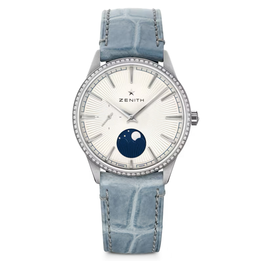The ZENITH Elite Moonphase Elite 692 36mm Watch by Zenith boasts a silver dial with a moon phase display at 6 o'clock, a textured blue alligator leather strap, thin silver hour markers, and is elegantly finished with a diamond-set bezel.