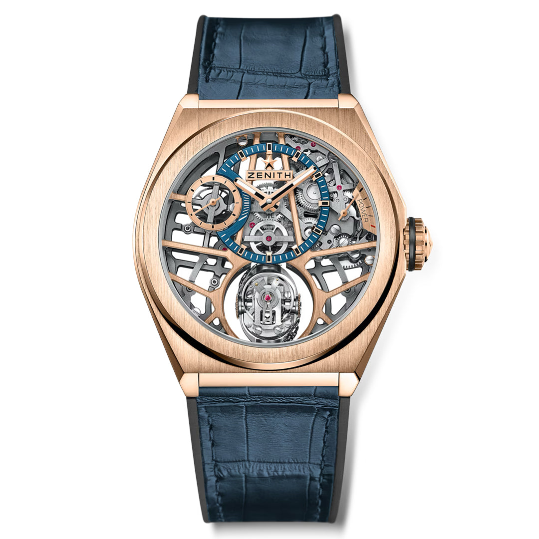 The ZENITH Defy Zero G El Primero 8812 S 44mm Watch features a gold case with a blue leather strap and an exposed mechanism, revealing its intricate workings and gravity control technology. The transparent face showcases numbered markers and the Zenith logo on the outer edge.