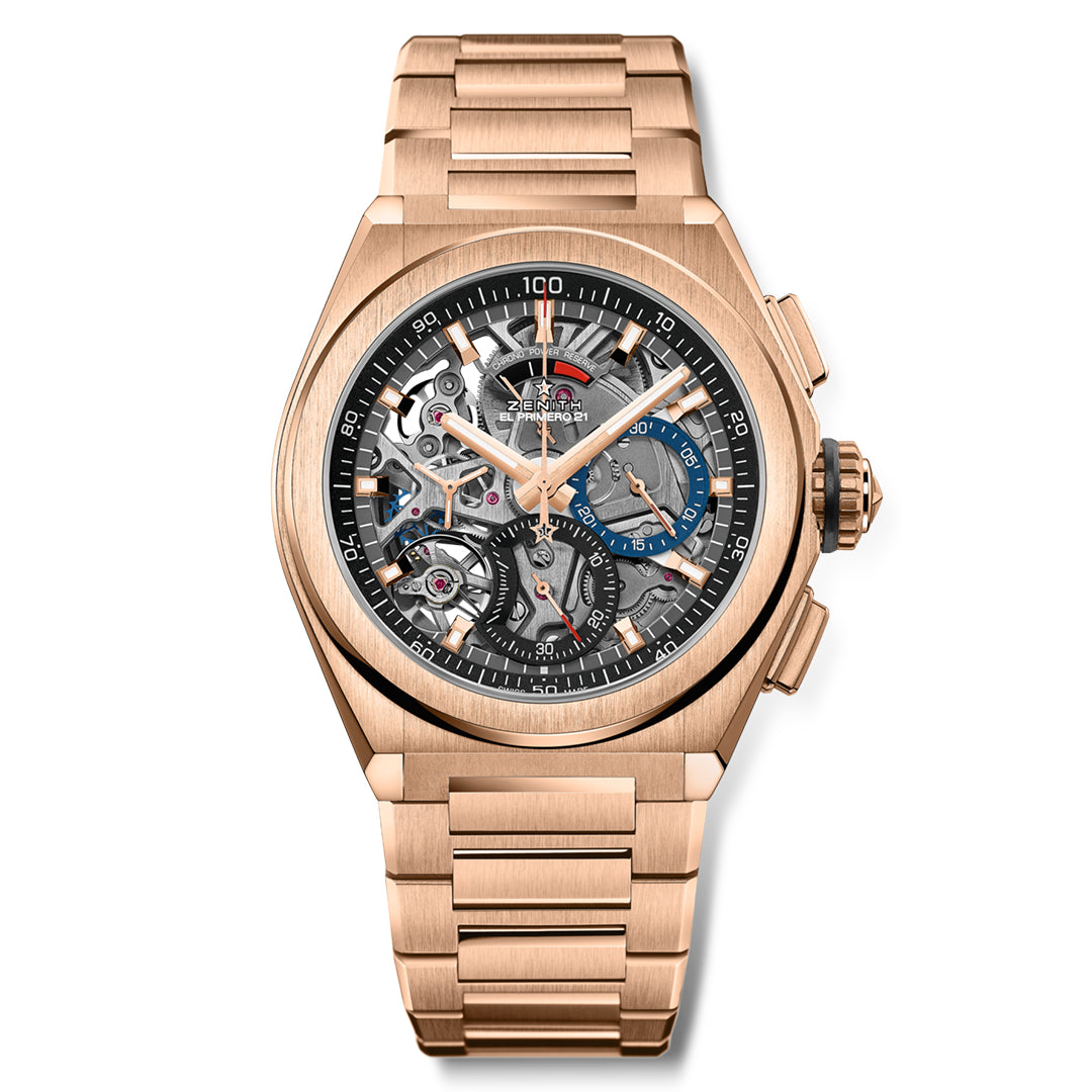 The ZENITH Defy El Primero 21 by Zenith is an 18k rose gold watch with a skeletal design, showcasing intricate gears and high-frequency escapements. It features a round face, black outer ring, 1/100th chronograph sub-dials, dual-tone metal bracelet, and gold and blue accents for added luxury.