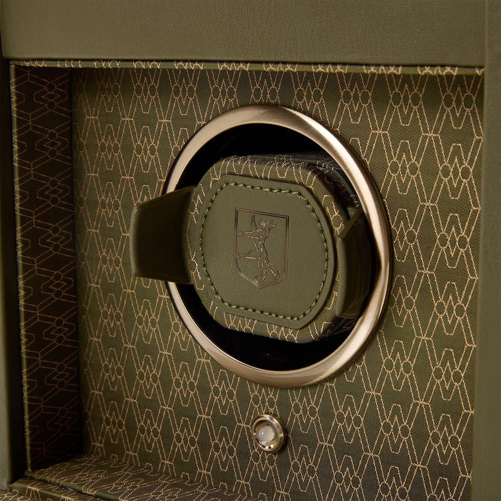 A close-up of the WOLF 1834 Earth Single Watch Winder reveals its luxury design and geometric pattern. It features a dynamic cuff with a circular holder adorned with leather accents and intricate stitching, nestled inside a box with a matching patterned interior, highlighting WOLF's patented innovation.