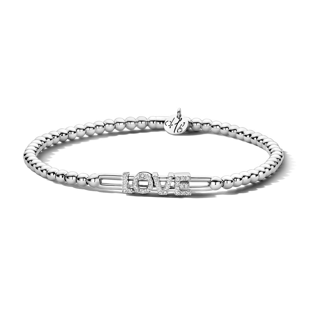 The Hulchi Belluni 18K White Gold Diamond Bracelet features a silver beaded design with "LOVE" in sparkling rhinestones and a small initial-engraved charm accented with 18K white gold near the clasp.