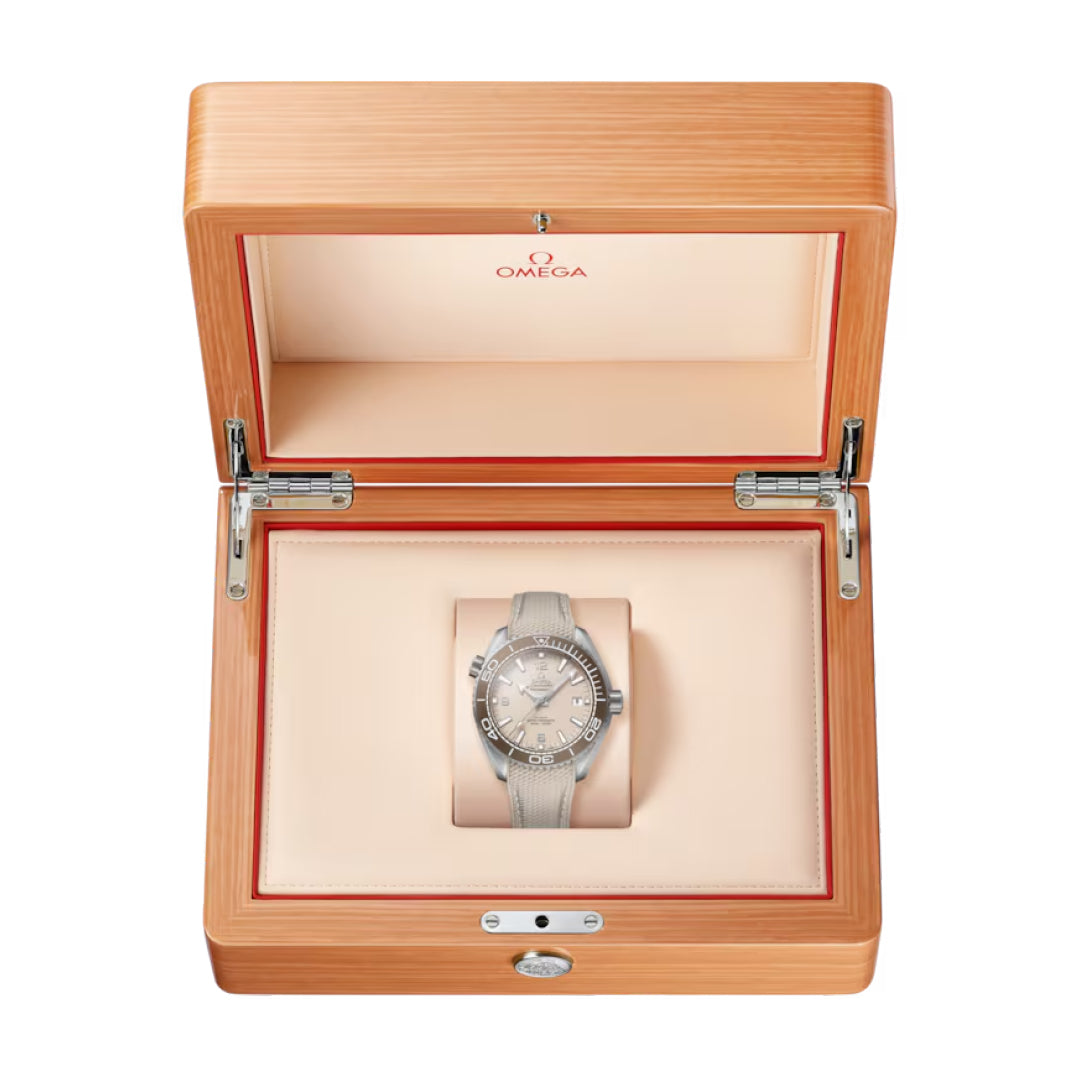 An OMEGA Seamaster Planet Ocean 600M Co-Axial Master Chronometer 43.5mm watch with a light strap is presented in an open, light wood OMEGA box featuring a cream interior and the OMEGA logo on the inside lid.