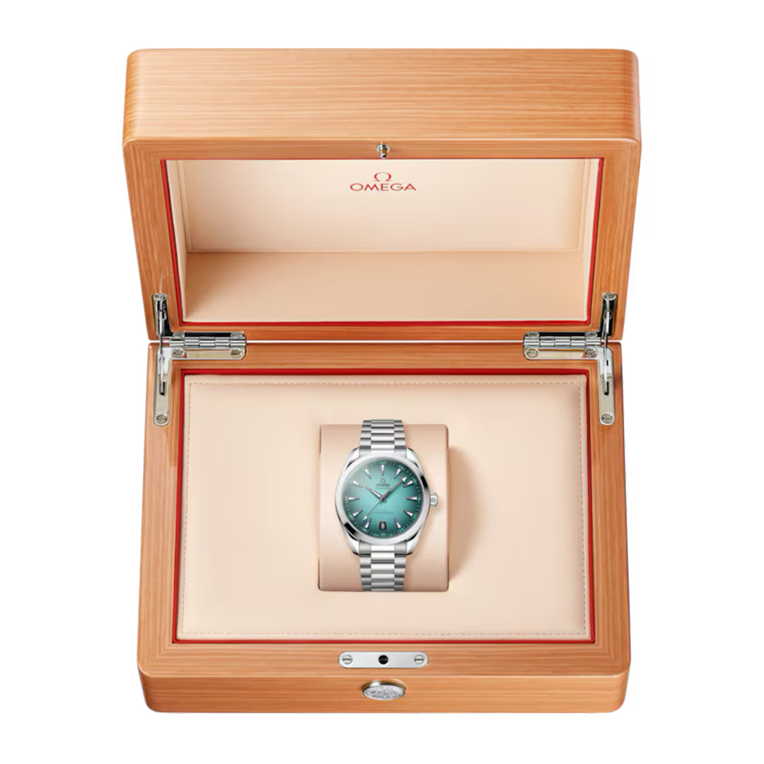 An OMEGA Seamaster Aqua Terra 150M Co-Axial Master Chronometer 41mm watch, featuring a teal face, is elegantly showcased in an open wooden box with a light cream interior and the Omega logo on the lid.