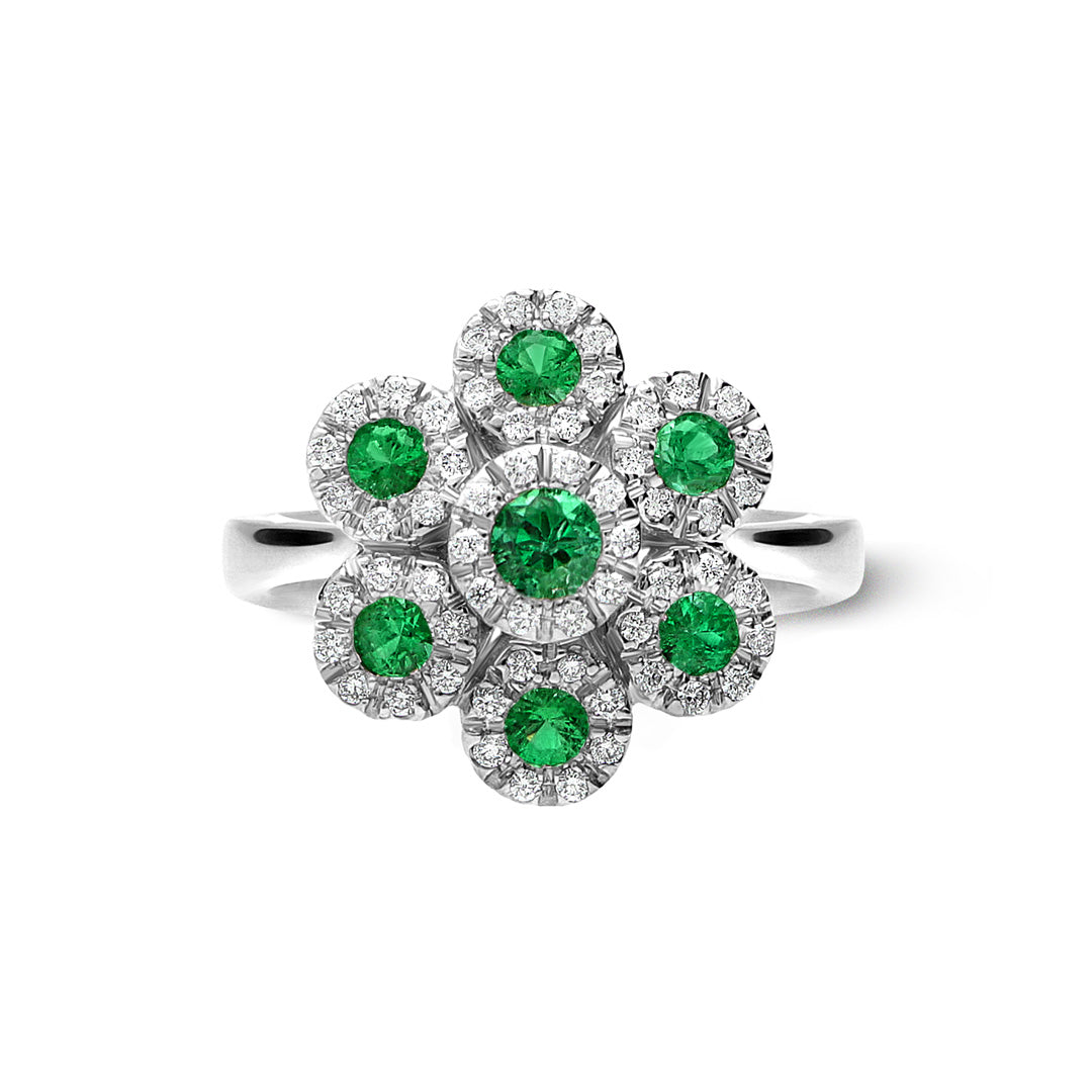 The Leo Pizzo Augusta Collection 18K White Gold Diamond Emerald Fashion Ring features a floral motif with a central green gemstone surrounded by six smaller emeralds, each encircled by diamonds, complemented by a sleek band for added elegance.