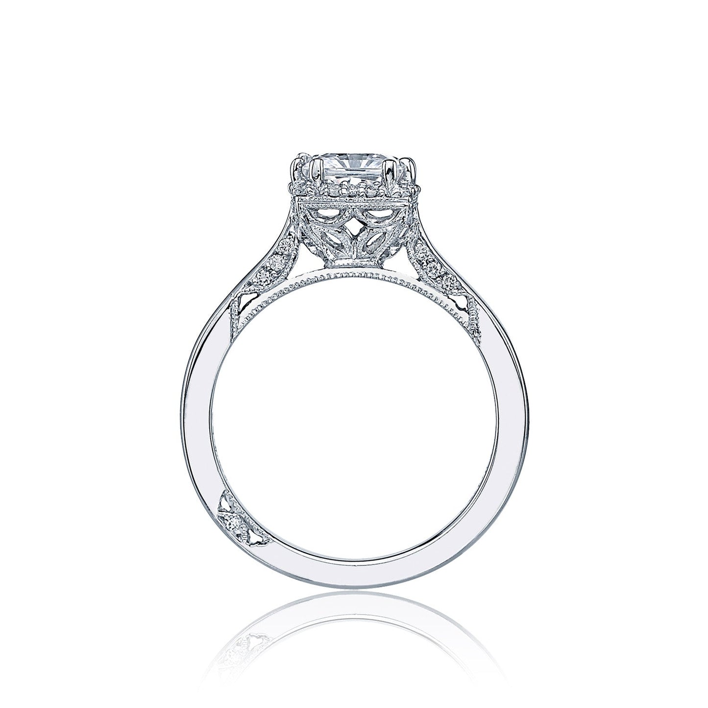 A side view of the exquisite Tacori Dantela engagement ring showcases a stunning princess cut solitaire in a detailed, ornate setting. Intricate cut-out patterns and smaller diamonds embellish the 18K white gold band, highlighting the expert craftsmanship of Tacori gemologists.