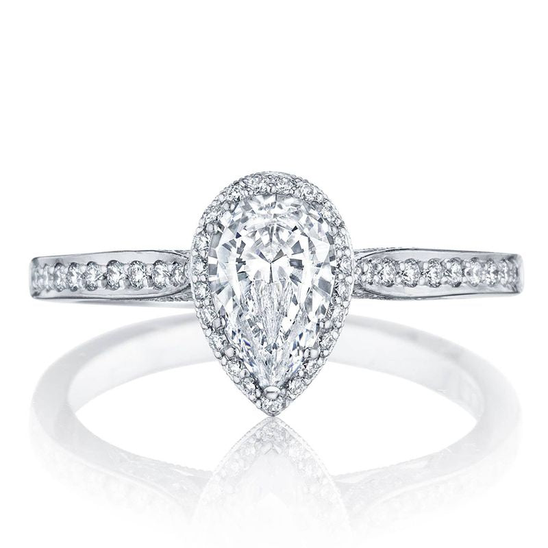 The Tacori Dantela 18K White Gold Pear Semi Mount with Diamond Band and Hidden Halo Engagement Ring features a captivating pear-shaped design, adorned with a halo of smaller diamonds on a sleek white gold band set with additional tiny diamonds. Crafted by Tacori, this elegant engagement ring is showcased beautifully against a plain white background.