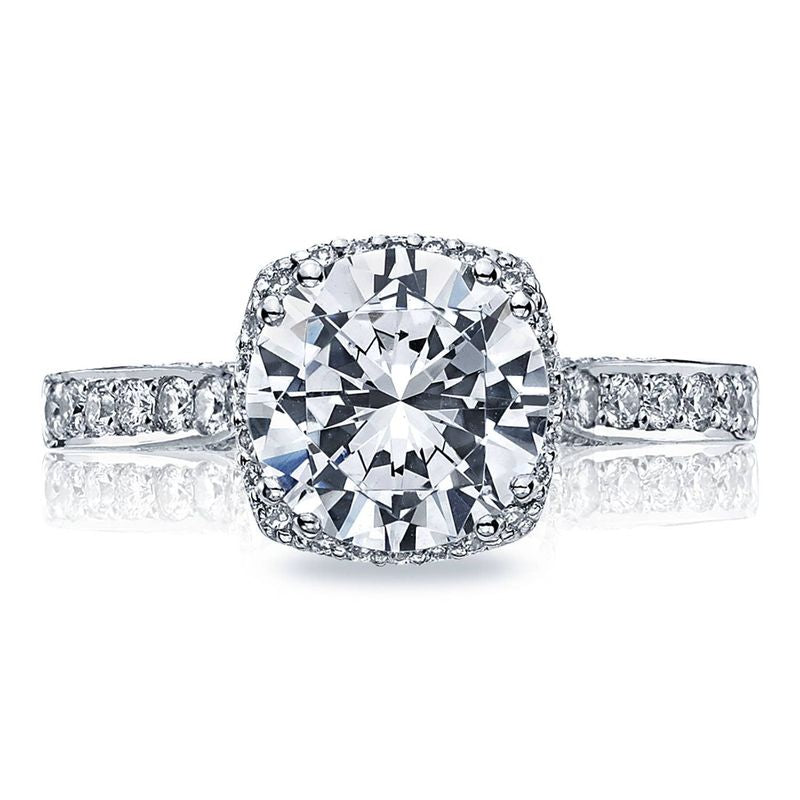 A close-up image showcases the Tacori Dantela Platinum Round Brilliant Semi Mount with Diamond Band and Hidden Halo Engagement Ring, featuring an exquisite round diamond at its center. Expertly crafted by Tacori gemologists, the band is adorned with smaller diamonds that amplify its sparkle. The central round brilliant diamond presents an elegant and luxurious design.