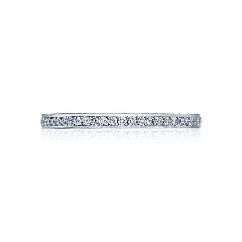 Presenting the Tacori Dantela 18K White Gold Round Brilliant Diamond Anniversary Ring: a sleek silver band adorned with small round diamonds encircling it, expertly crafted by Tacori and showcased against a simple white backdrop.