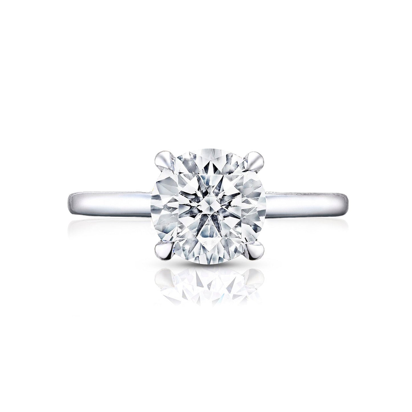 A Tacori Simply engagement ring, crafted from 18K white gold, features a single large round brilliant diamond in a four-prong setting. The smooth and polished band elegantly reflects light and includes diamond accents. Centered on a white background, this exquisite piece by Tacori highlights the elegance and simplicity characteristic of premium engagement rings.