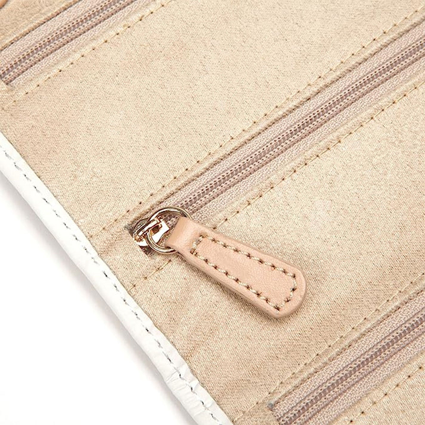 Close-up of the WOLF 1834 Chloe Jewellery Portfolio in beige, showcasing its two zippered compartments. This elegant accessory displays zippers enhanced with brown stitching and leather pulls, complemented by white-trimmed edges.