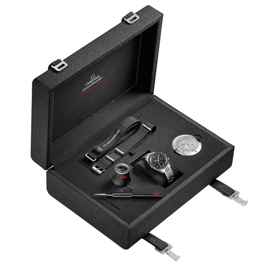 A black OMEGA presentation box houses the Speedmaster Calibre 321 Chronograph 39.7mm watch, a magnifying loupe, metal badge, strap-changing tool, and extra straps—all neatly organized in custom compartments.