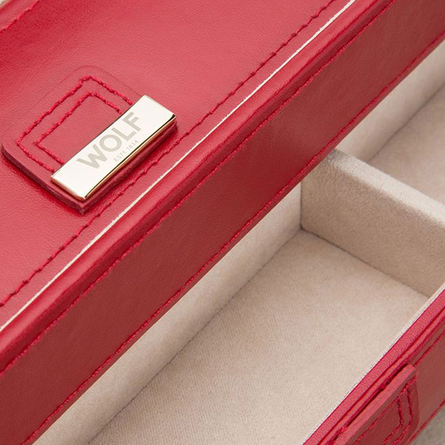 Close-up of an open WOLF 1834 Caroline Red Large Jewellery Box crafted in diamond-quilted red leather with soft beige interior compartments. The lid features a gold-tone plaque with the brand name "WOLF," complemented by advanced LusterLocâ„¢ technology for enhanced protection.