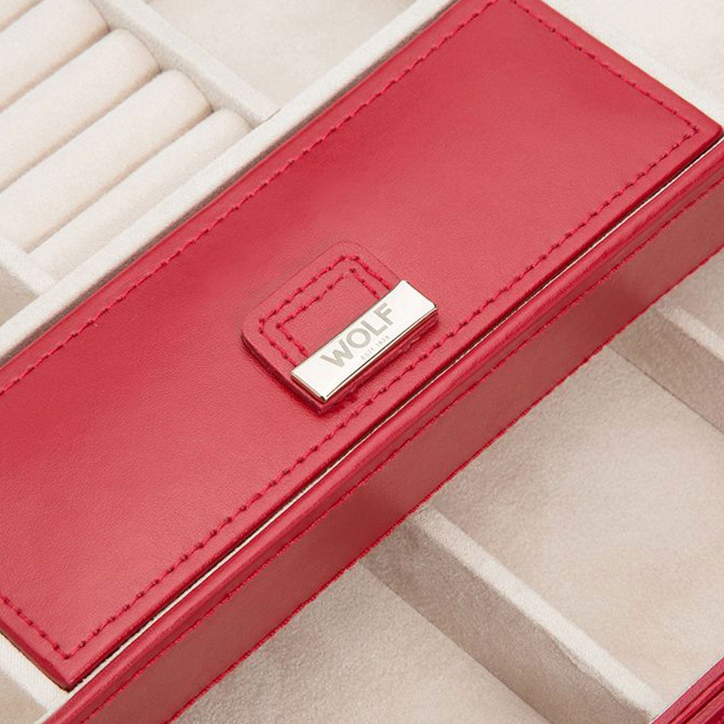 Close-up of the WOLF 1834 Caroline Red Jewellery Box in diamond quilted leather, featuring a silver plate with the inscription "WOLF" on the lid. The interior is crafted with LusterLocâ„¢ technology and offers compartments for rings and other accessories, designed in a soft beige finish.