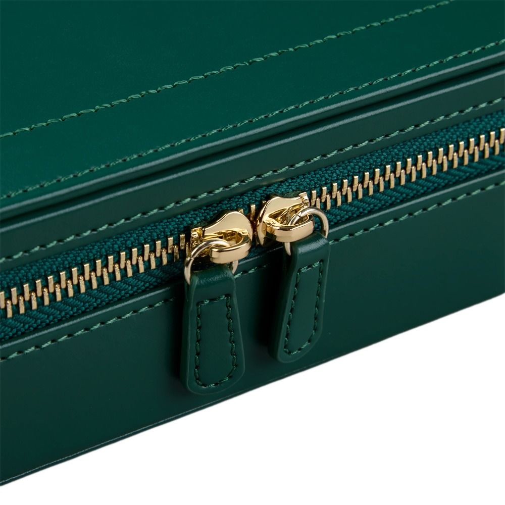 Close-up of the WOLF 1834 x Fiona Howard Sophia Travel Zip Case in Forest Green Fruit Botanical, featuring diamond-quilted green leather, a gold zipper with dual pull tabs, and visible stitching along the edge. The zipper is partially closed.