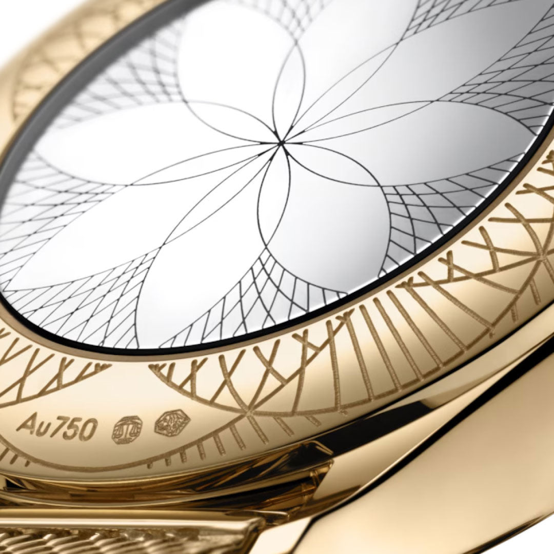 Close-up of the OMEGA De Ville Mini Tresor Quartz 26mm, showcasing a Moonshine™ Gold bezel with intricate geometric engravings and a flower-like dial design. Hallmarks and "Au750" for 18k gold are engraved on the edge.