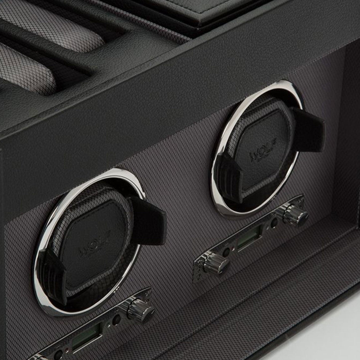 The WOLF 1834 Viceroy Black Watch Winder embodies the elegance of a skilled designer's touch, with its two circular compartments accented in chrome and lined with luxurious black fabric interiors. Crafted by the renowned brand WOLF, this watch winder is set in a textured carbon-fiber-like material, reflecting refinement and innovation through its high-quality materials.