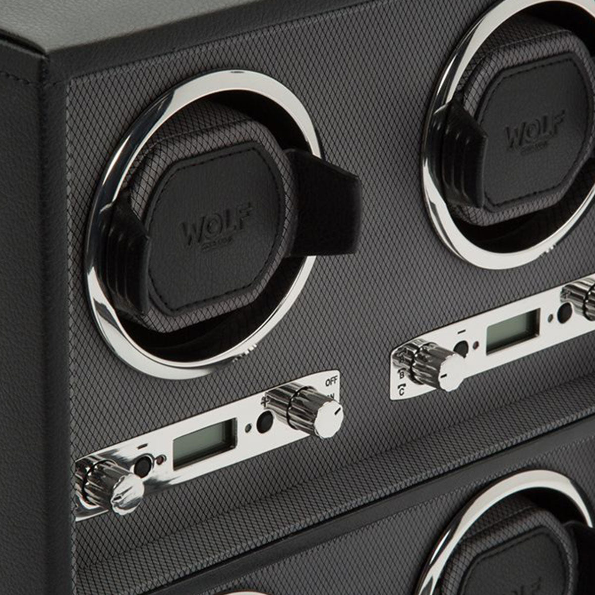 Close-up of the WOLF 1834 Viceroy Black Watch Winder, showcasing its textured black surface and chrome details. It includes slots for holding watches, buttons, and digital displays for precise settings. The brand name "WOLF" is prominently displayed on the holder, emanating a modern classic aesthetic.