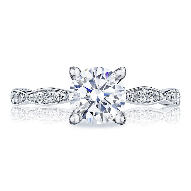 A dazzling Tacori Sculpted Crescent engagement ring showcases a prominent round-brilliant diamond set in an 18K white gold band. The band is adorned with intricate diamond patterns, exemplifying the elegance and brilliance of TACORI gemologists' craftsmanship.