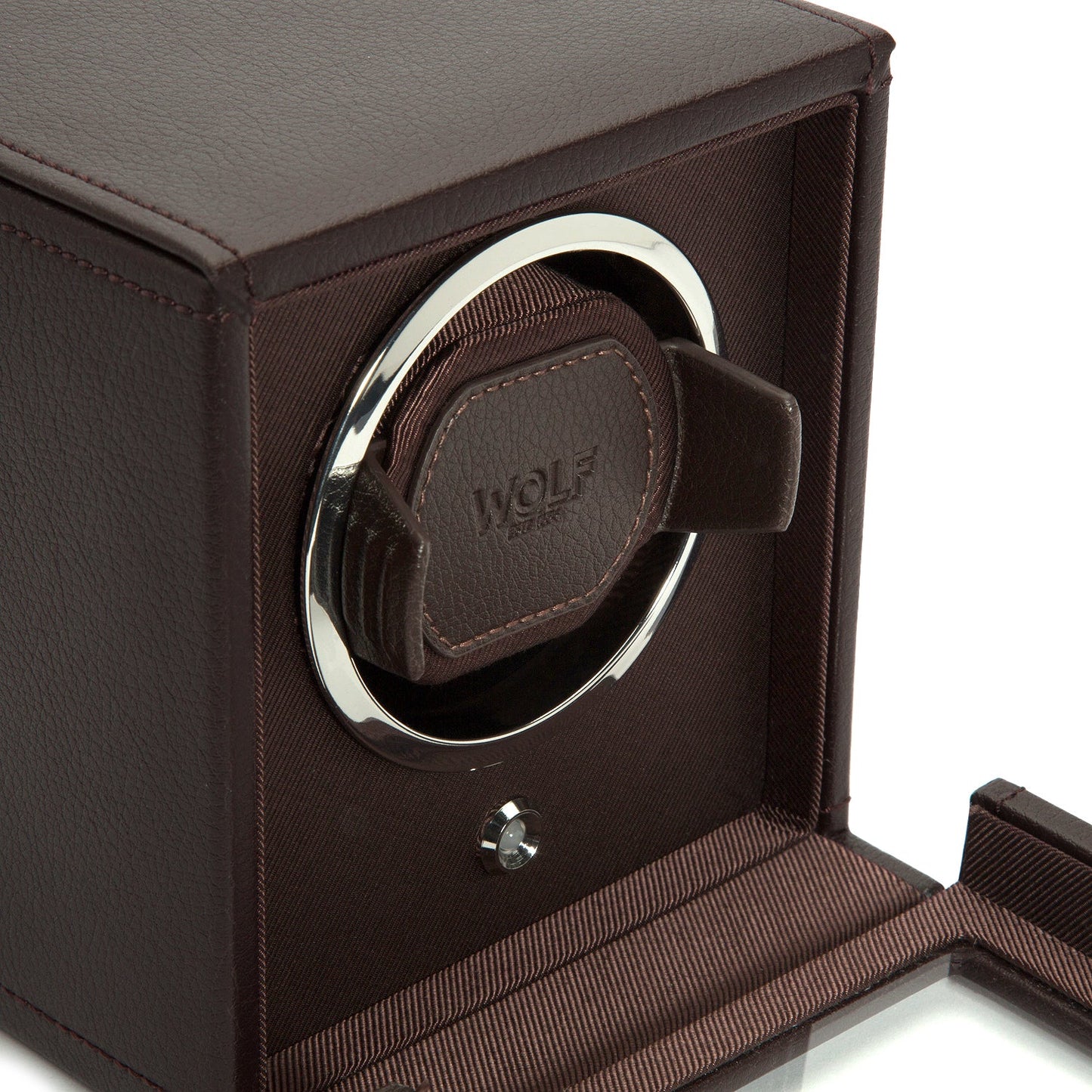 The WOLF 1834 Cub Single Watch Winder With Cover features a stylish brown vegan leather exterior and a transparent door, complemented by an interior of dark fabric lining. It incorporates patented rotation technology to ensure your automatic watches remain wound when not in use.