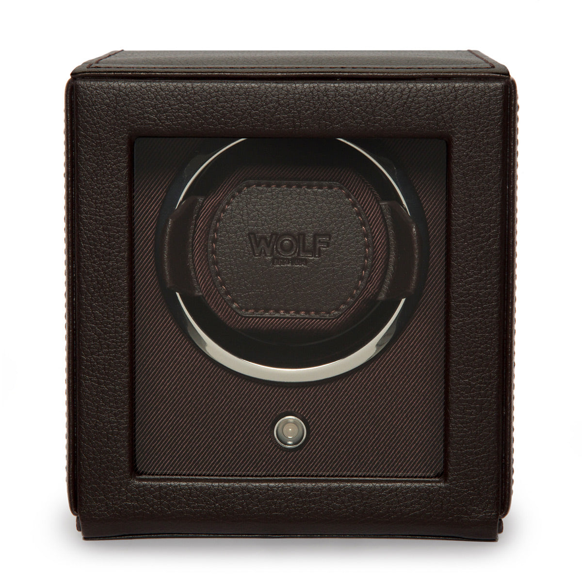 The WOLF 1834 Cub Single Watch Winder With Cover, crafted from brown vegan leather with a transparent front, prominently showcases the "Wolf" logo. Its interior features plush cushioning engineered to securely hold and rotate a watch using its patented rotation system. This sleek, cubic winder includes a conveniently positioned button at the bottom center for easy operation.