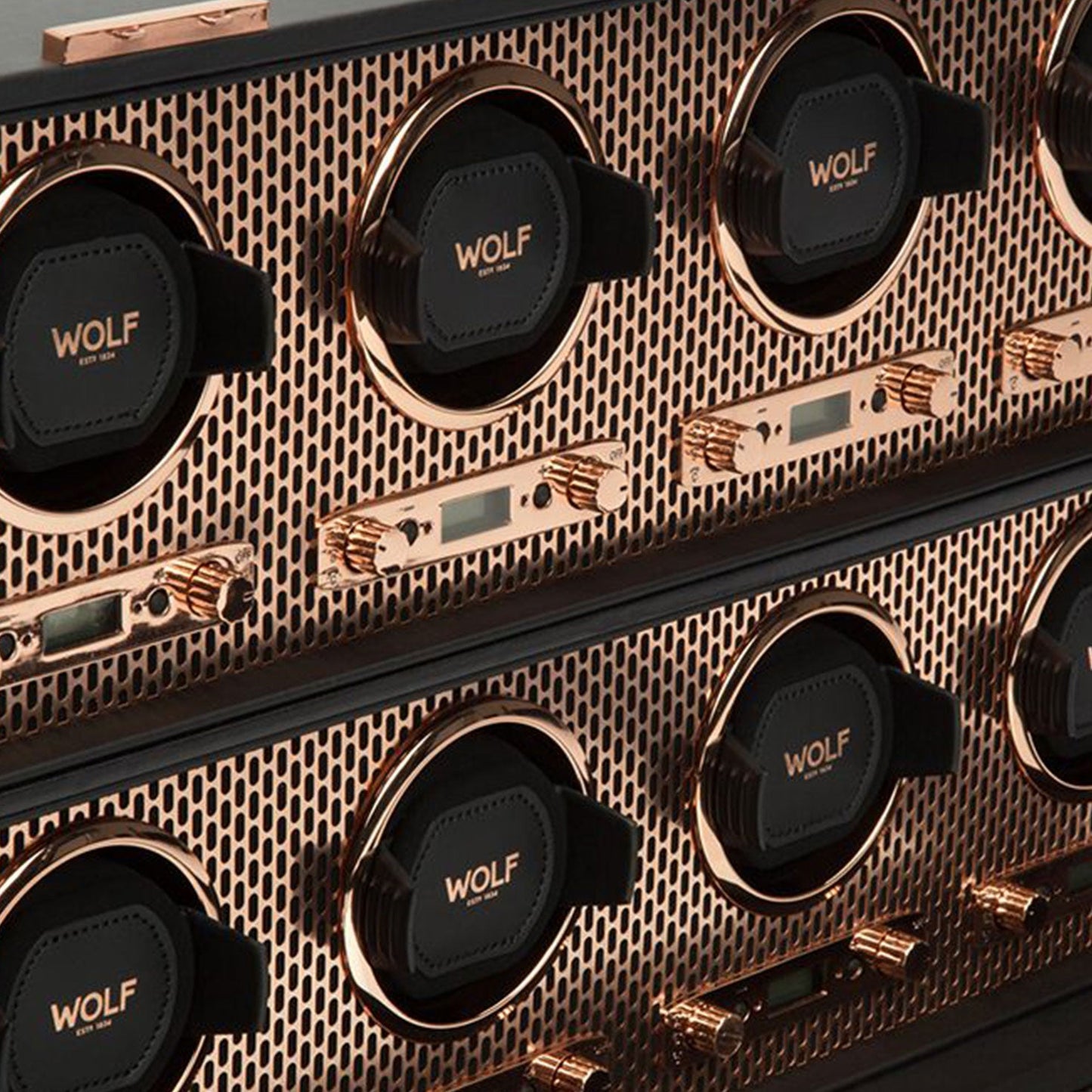 Close-up of the WOLF 1834 Axis 8 Piece Winder, designed with an elegant metallic, honeycomb-patterned finish. It includes multiple winding slots prominently displaying the "WOLF" branding. The winders combine copper laser-cut details with black elements, providing a refined look enhanced by patented technology.