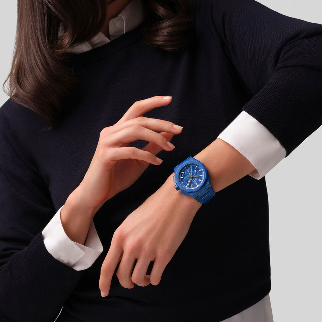 A person in a black sweater with white cuffs adjusts a ZENITH Defy Skyline Chronograph 160th Anniversary Limited Edition El Primero 3600 42mm Watch on their left wrist, set against a light gray background that highlights Zenith's Swiss watchmaking expertise.