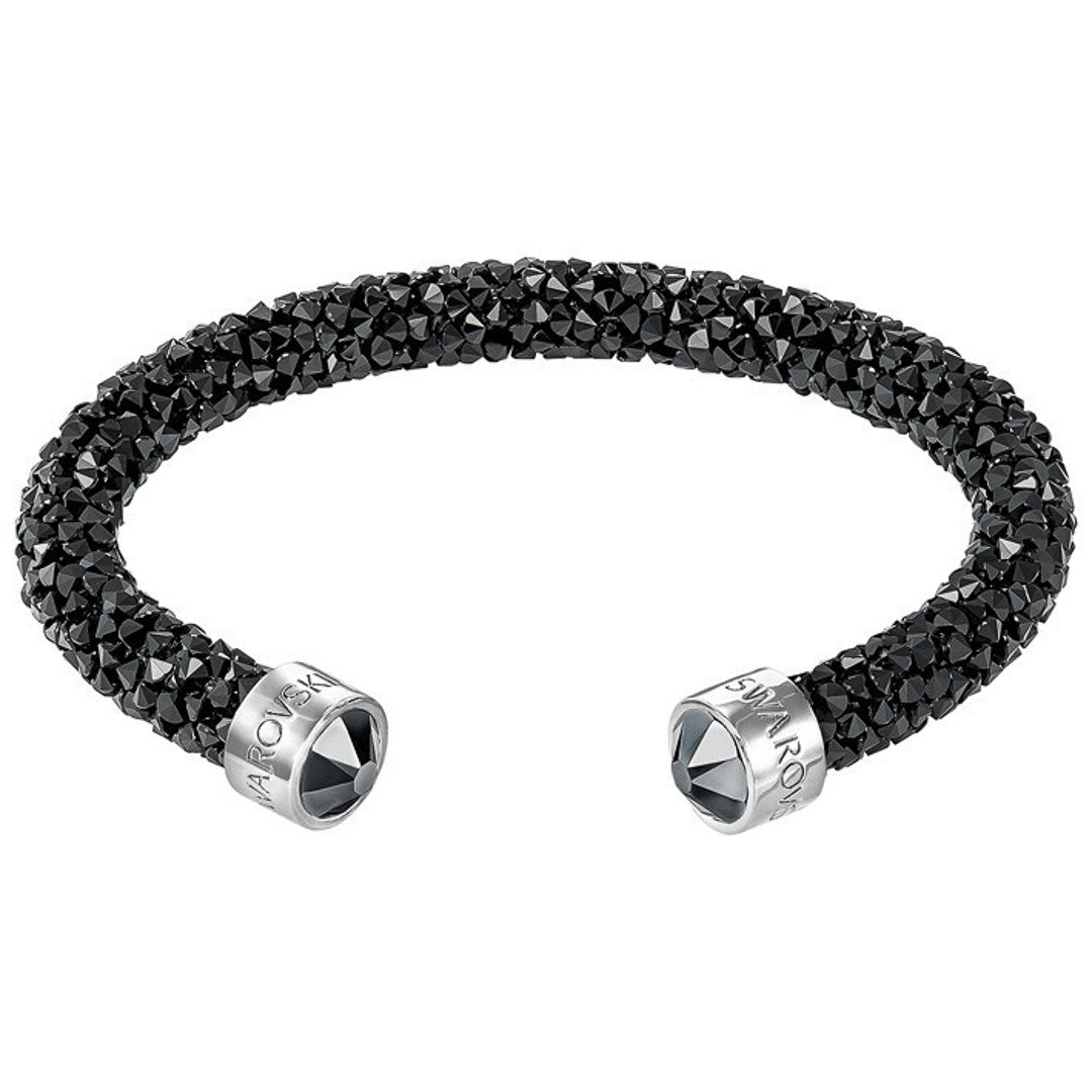 Discover the Swarovski Crystal Dust Cuff, a sleek and elegant black crystal-studded open bangle adorned with silver metal caps featuring engraved brand logos. This exquisite piece from Swarovski combines texture and shine with a touch of sparkling crystals.