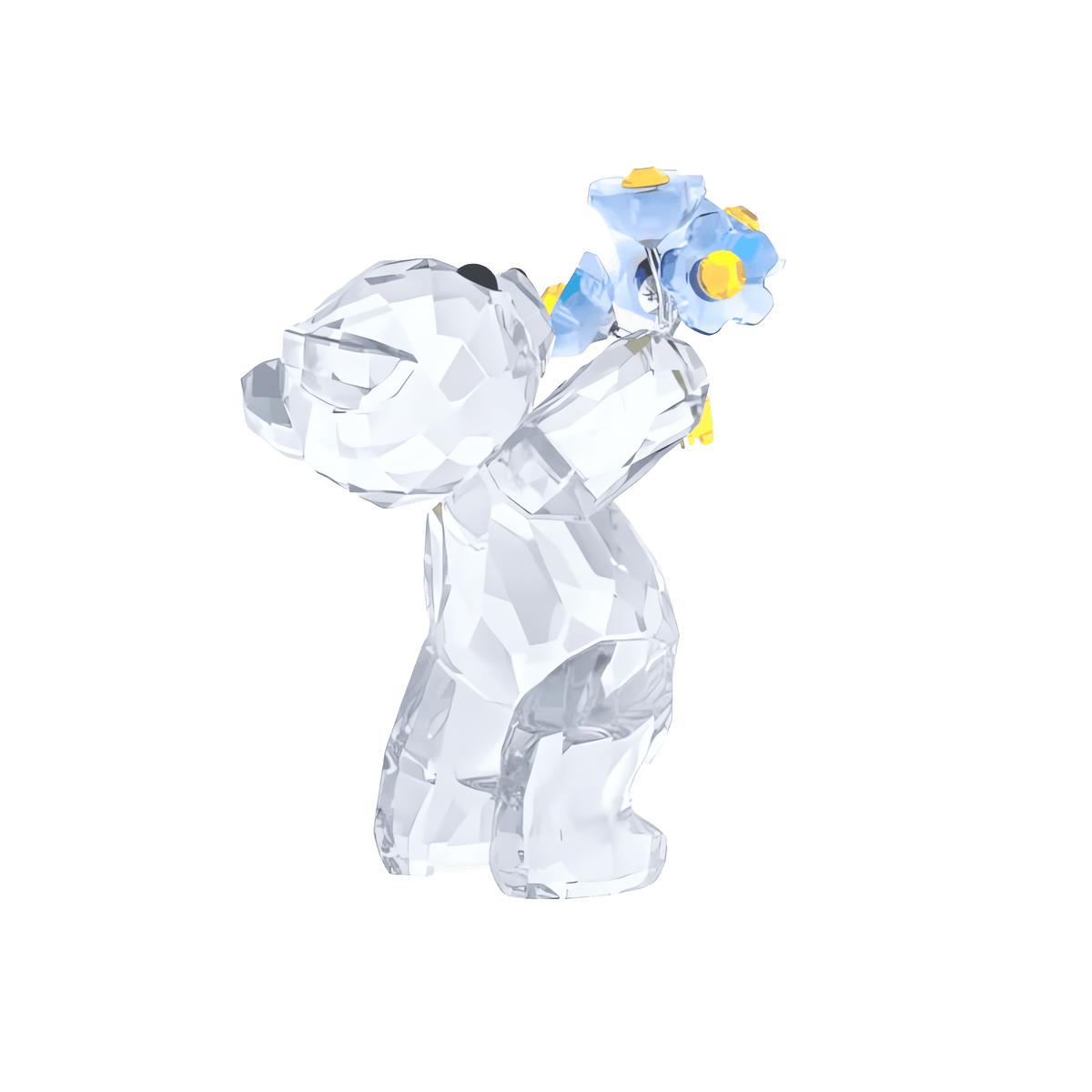 The Swarovski Kris Bear - Forget-me-not by Swarovski is a faceted crystal bear figurine that stands upright, holding a small bouquet of forget-me-not flowers behind its back, displayed on a white background.