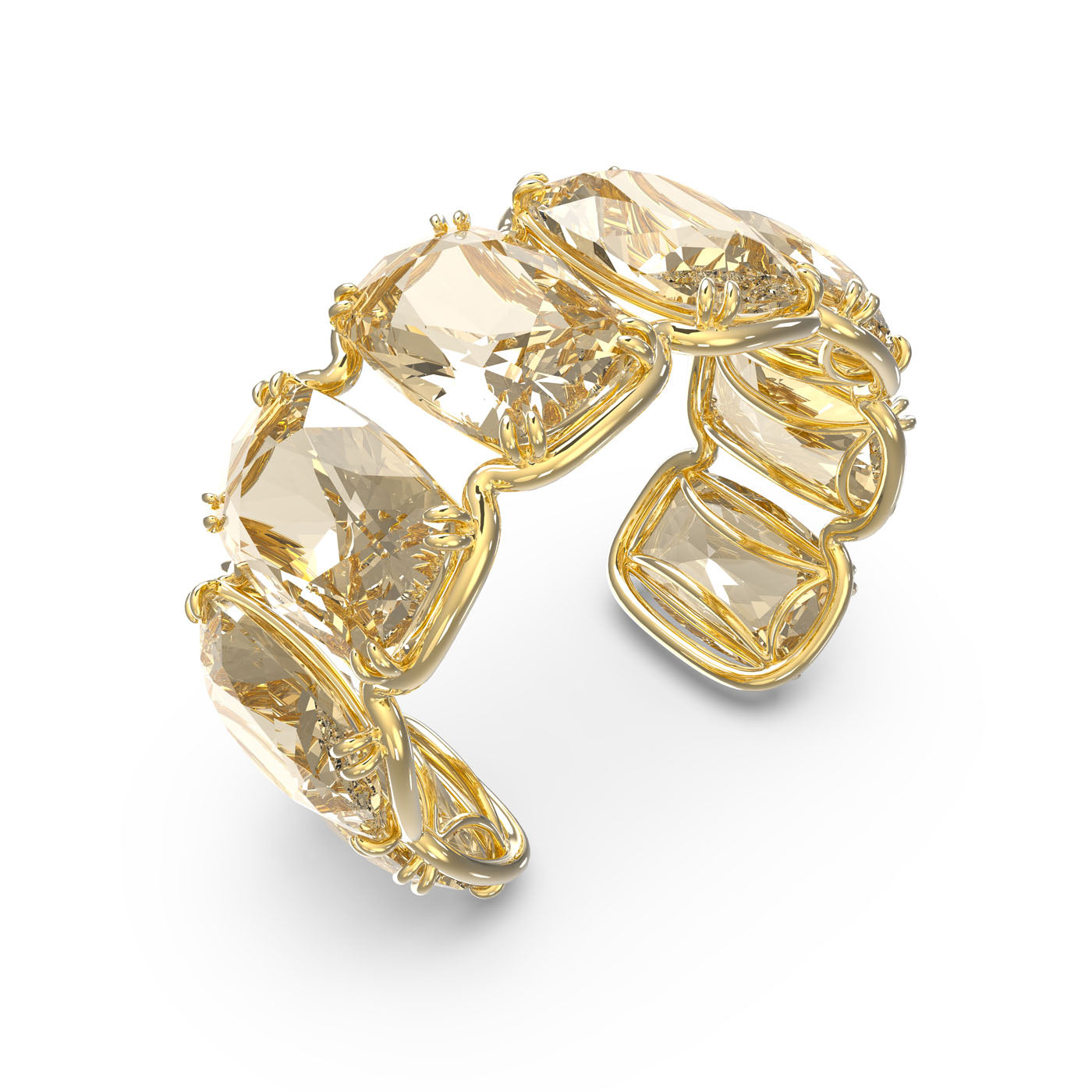 The Swarovski Gold Tone Oversized Floating Crystals Harmonia Cuff by Swarovski is adorned with elongated cushion-cut crystals, elegantly arranged in a continuous band against a white background.