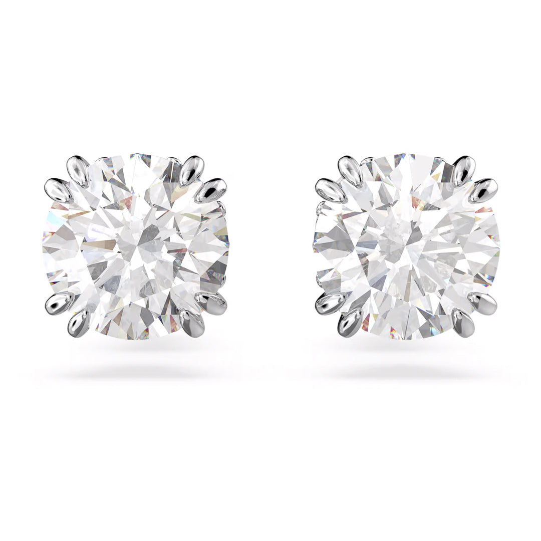 The Swarovski Stilla Stud Earrings by Swarovski are a sophisticated pair that showcase round, sparkling zirconia stones set in a rhodium-plated silver or white gold prong setting. Photographed against a plain white background, the earrings brilliantly reflect light through their multiple facets.