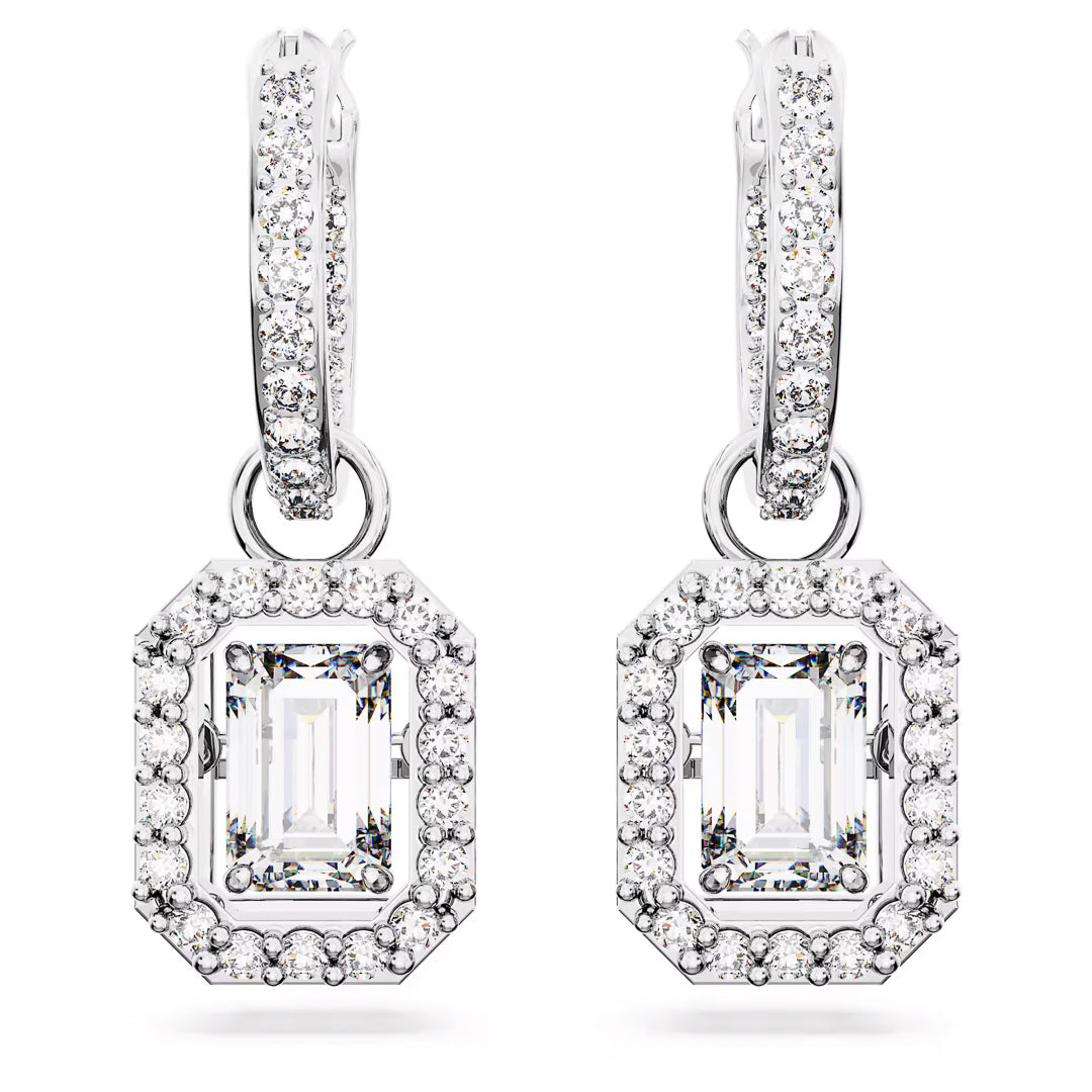 The Swarovski Una Drop Earrings by Swarovski showcase an elegant design with white gold and an intricate rhodium-plated finish. These earrings feature a rectangular gemstone, surrounded by smaller sparkling stones, gracefully hanging from a diamond-studded hoop, adding a luxurious and sophisticated touch.