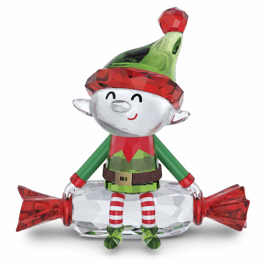 Add a touch of festivity to your home with the Swarovski Holiday Cheers Dulcis Elf Home Décor, showcasing a cheerful elf adorned with a green and red hat and striped leggings, comfortably seated on an oversized crystallized candy figurine with red ends.