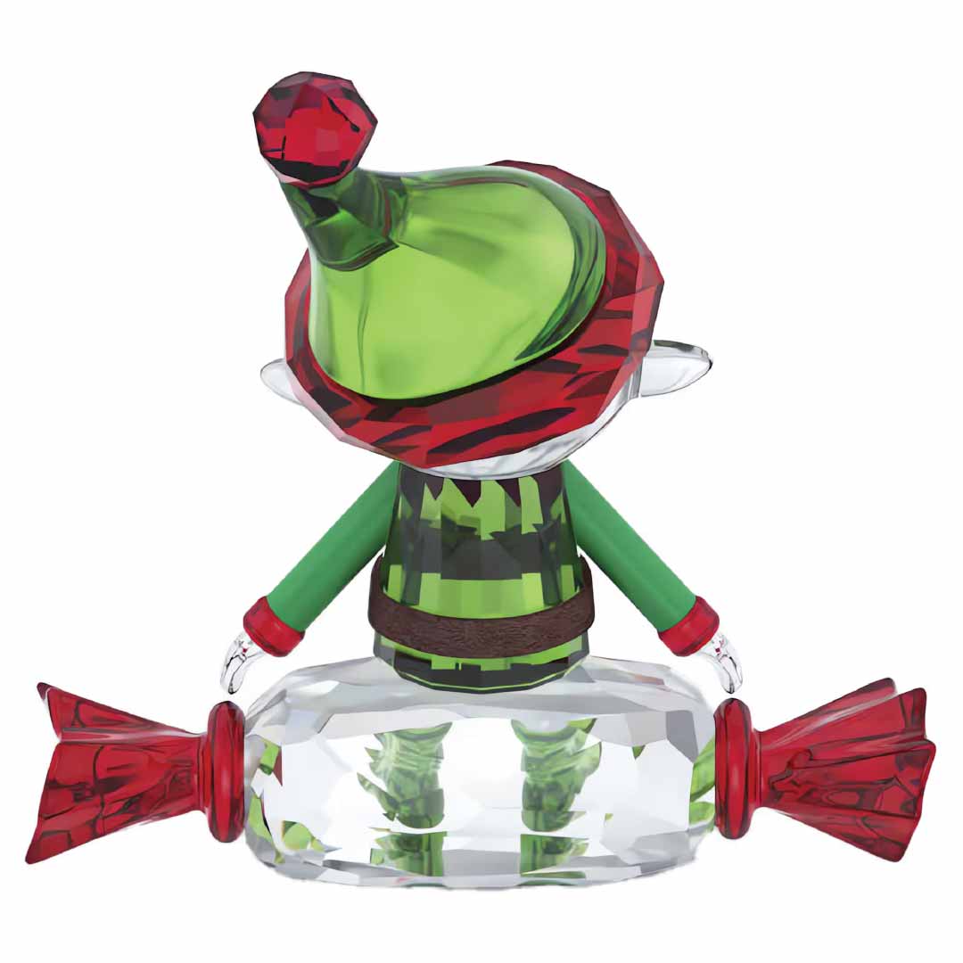 The Swarovski Holiday Cheers Dulcis Elf Home Décor features a charming crystal figurine of an elf dressed in a green and red outfit perched on a clear, candy-shaped base. With its pointed hat and festive ensemble facing outward, it brings holiday charm to any collection.