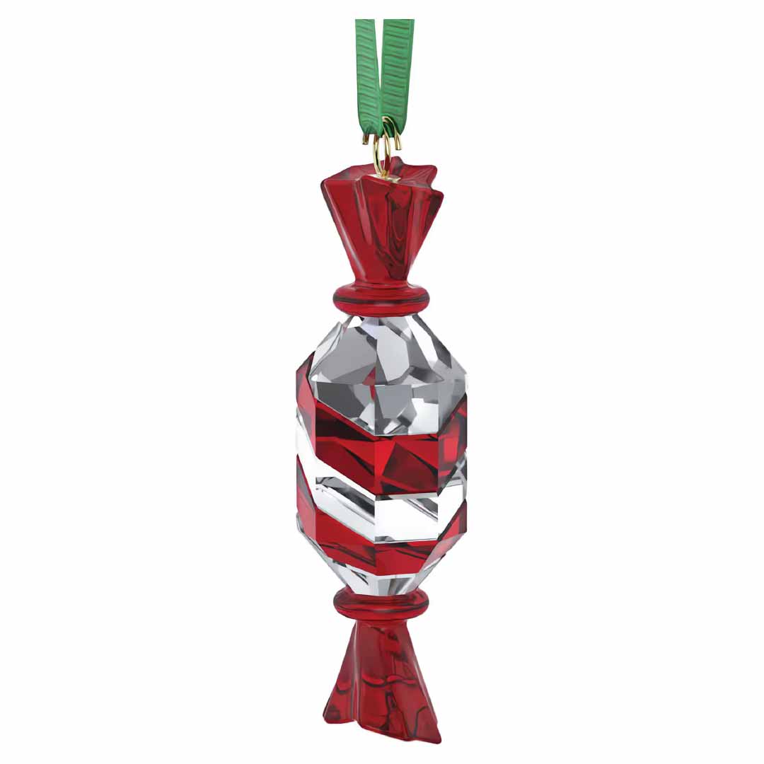 The Swarovski Holiday Cheers Dulcis Crystal Ornament, featuring a figurine shaped like a wrapped sweet with radiant red and clear stripes, hangs from a green ribbon, making it the perfect addition to enhance your holiday décor.